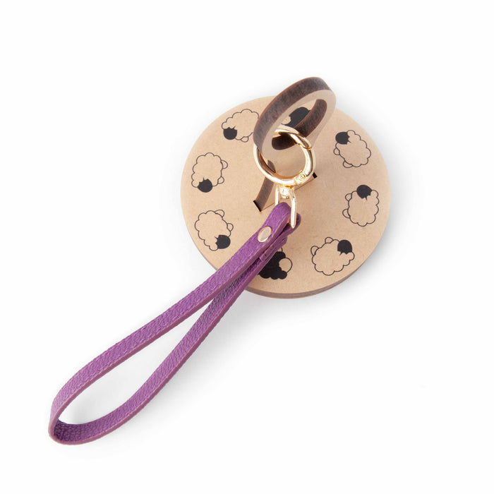 Plum Wide Ring wrist strap on Twice Sheared Sheep branded round kraft packaging card with sheep illustrations and gold spring ring clasp