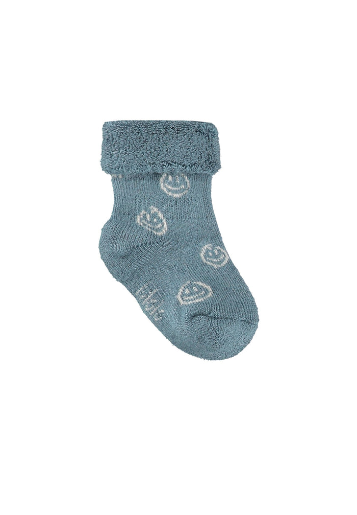 Blue baby sock with smiley face pattern on a white background
