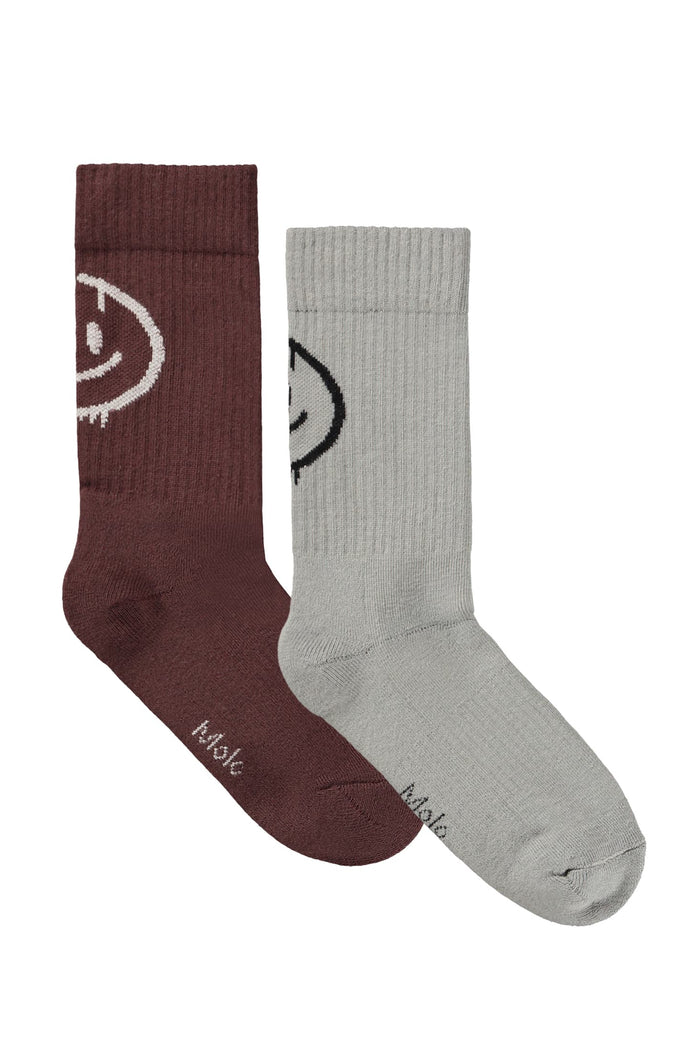 Two socks, one burgundy and one gray, with smiley face designs on a white background.