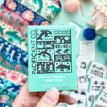 Hand holding the mint green Ocean 2 Doodle Card Deck by Pacific Knit Co tuckbox