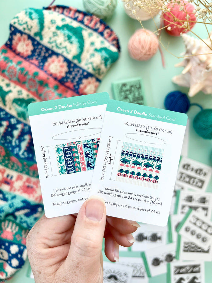 Hand holding the Ocean 2 Doodle Infinity Cowl and Standard Cowl schematic cards