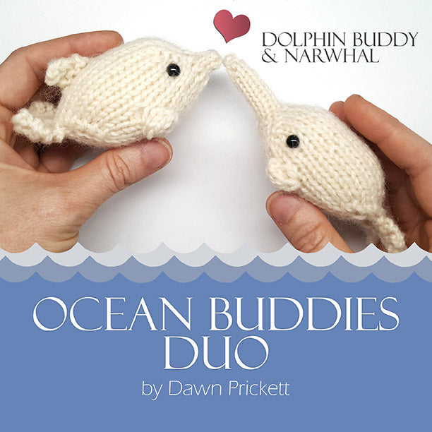 Two hands holding cream knitted dolphin and narwhal toys with Ocean Buddies Duo title and wave border