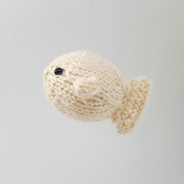 Cream knitted puffer fish toy from the Ocean Buddies Duo set shown from above on white background, displaying the round body and small tail fin