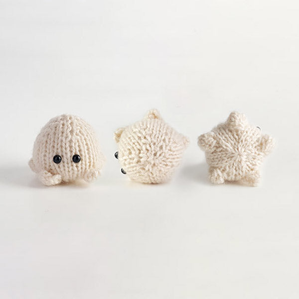 Three small knitted cream sea creatures including a seal, puffer fish, and starfish from Ocean Buddies pattern collection