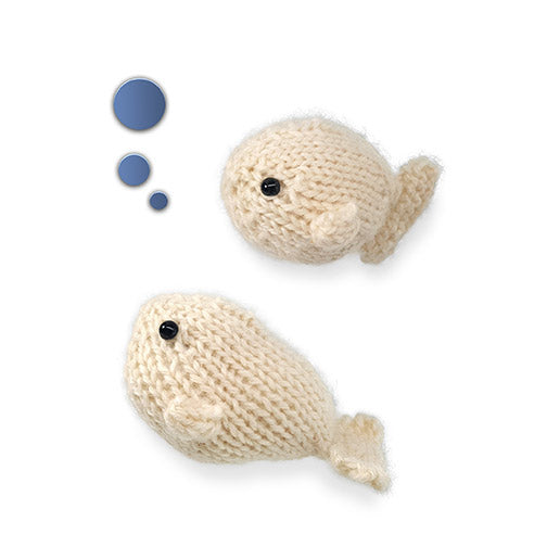 Two cream knitted Ocean Buddies toys — a small round fish at the top with blue bubble accents and a larger whale with a curled tail below