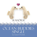 Two cream knitted seahorse toys facing each other with pink heart above ocean wave border