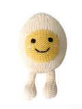 A knitted plush toy shaped like a smiling fried egg, with a cream-colored body and legs and a yellow face with embroidered black eyes and mouth.
