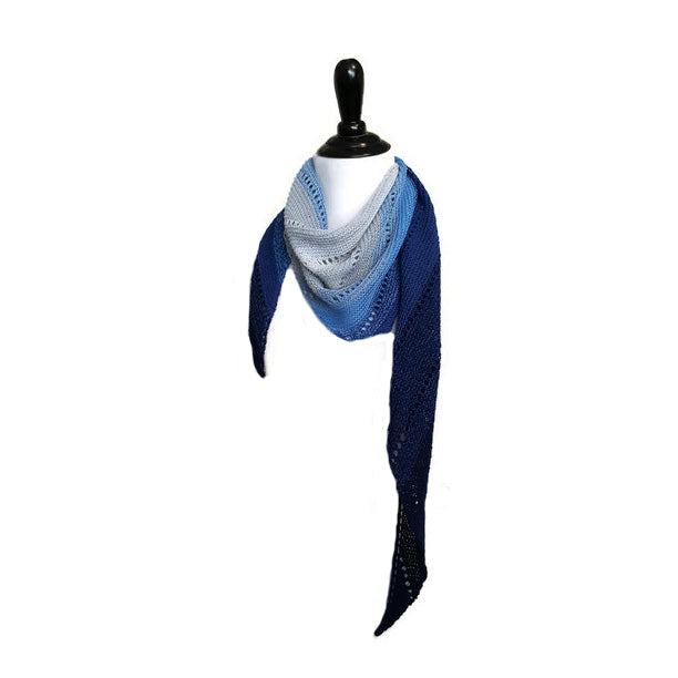 Pathway scarf in gradient blue and white worn as a triangle shawl on a mannequin with one tail hanging down to show the asymmetric shape