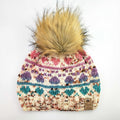 Colorwork knit beanie with pawprint motifs in pink, purple, and teal on cream with faux fur pom-pom