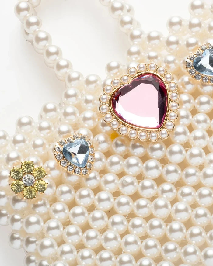 Pearl necklace with heart-shaped gemstones on a white background