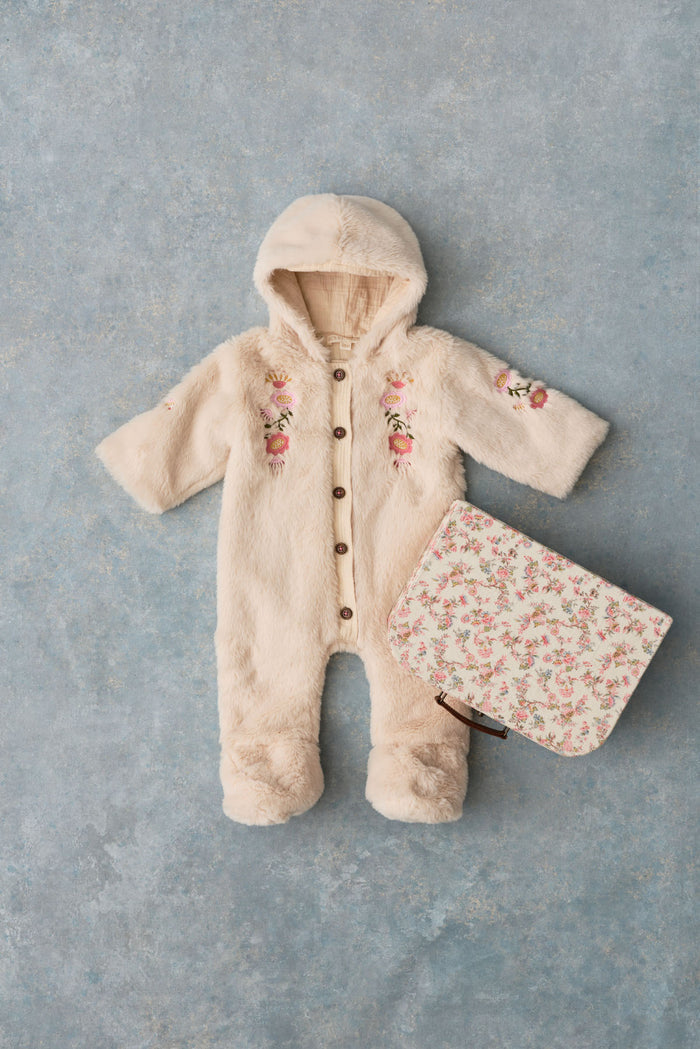 faux fur baby romper with floral suitcase on grey backdrop.