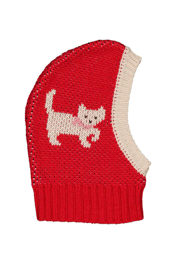 A red knit balaclava with a cream-colored knitted side panel and a knitted cat motif on the front, shown against a plain white background.