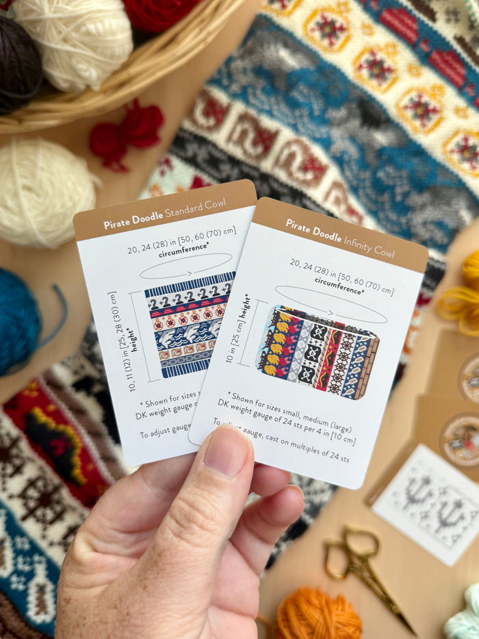 Hand holding the Pirate Doodle Standard Cowl and Infinity Cowl schematic cards