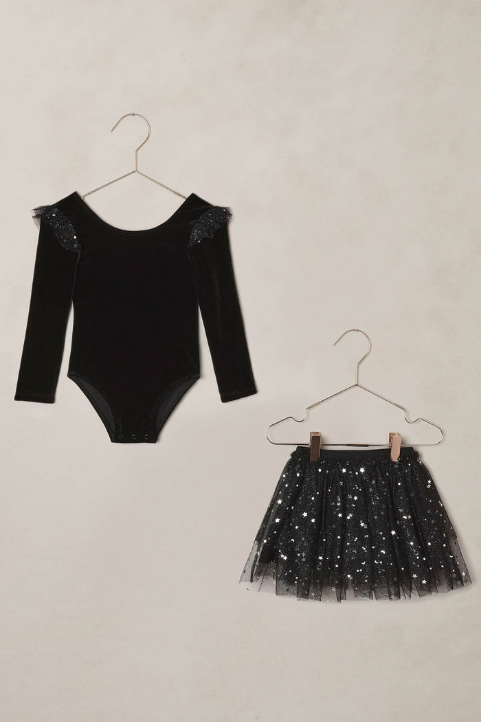 Black velvet bodysuit with sheer sleeves and black sequin skirt on hangers against a beige background