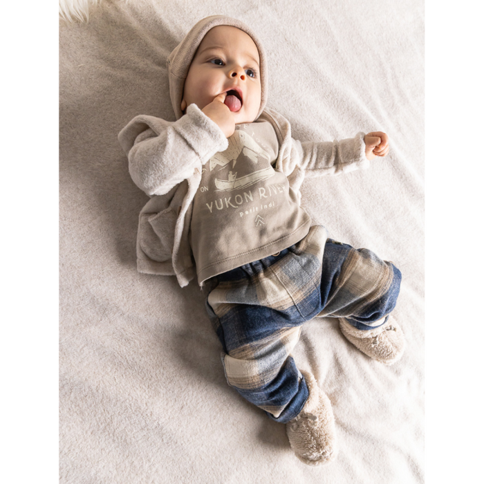 Baby wearing a gray hoodie and blue striped pants on a white blanket