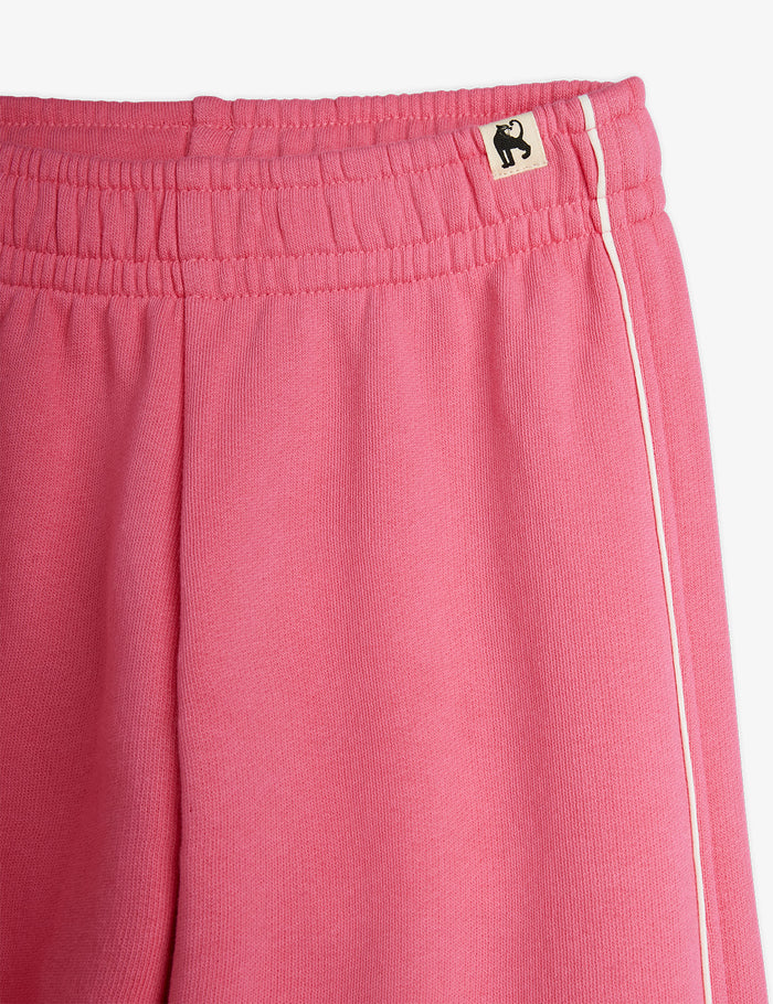 Close-up of pink sweatpants with a brand logo on a white background
