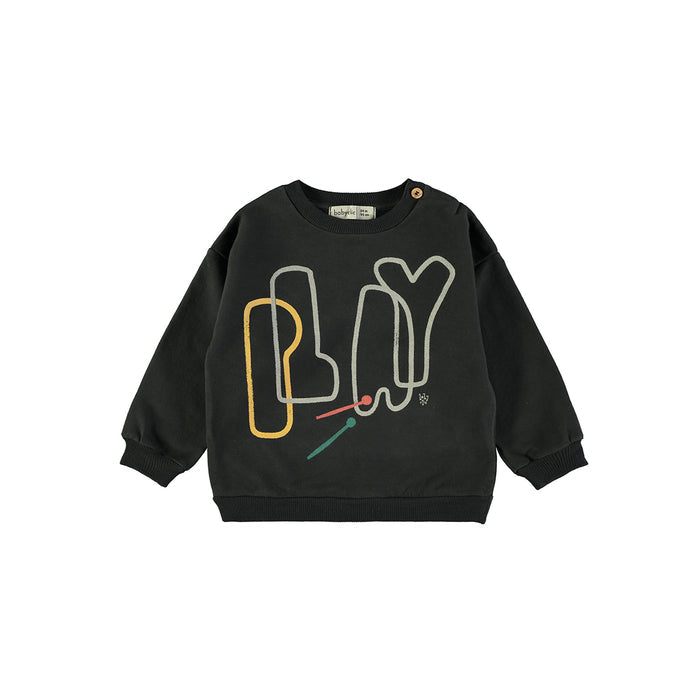 A black long-sleeve sweatshirt with a graphic design on the front featuring the word 'PLAY' in stylized, overlapping letter outlines of yellow, white, and light green, accented with small red and teal mallets.