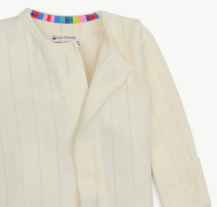 Close-up of a cream-colored baby one piece with a colorful striped inner collar and a visible 'eco-friendly' label.
