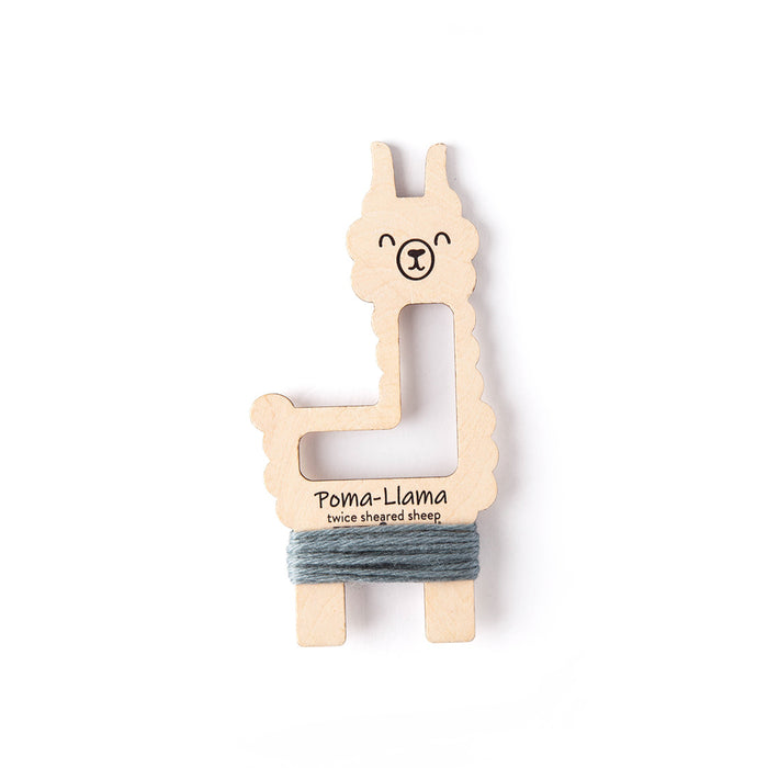 Poma-Llama tool with grey-blue Dove yarn wrapped around its full body showing tassel wrapping position on a white background