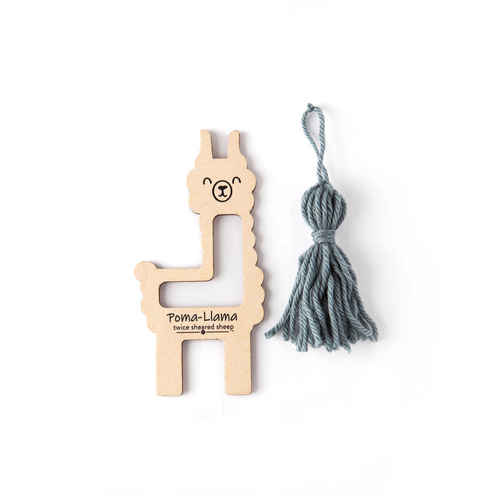 Poma-Llama tool beside a finished grey-blue Dove yarn tassel showing the completed tassel result on a white background