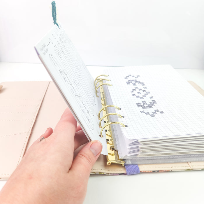 Side view of the Project Journal Planner opened showing the thickness of included pages with project detail sheets and graph paper with a hand-drawn chart