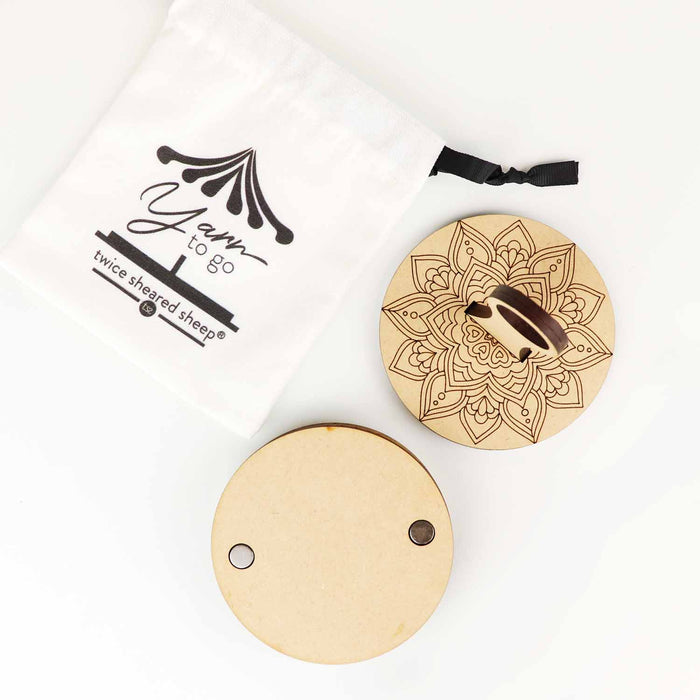 Mandala Yarn To Go Carousel shown disassembled — a round wooden top disc with a printed mandala design and center post, a plain carousel base with magnetic closures, and a white cotton drawstring storage bag printed with the Yarn To Go and Twice Sheared Sheep logos