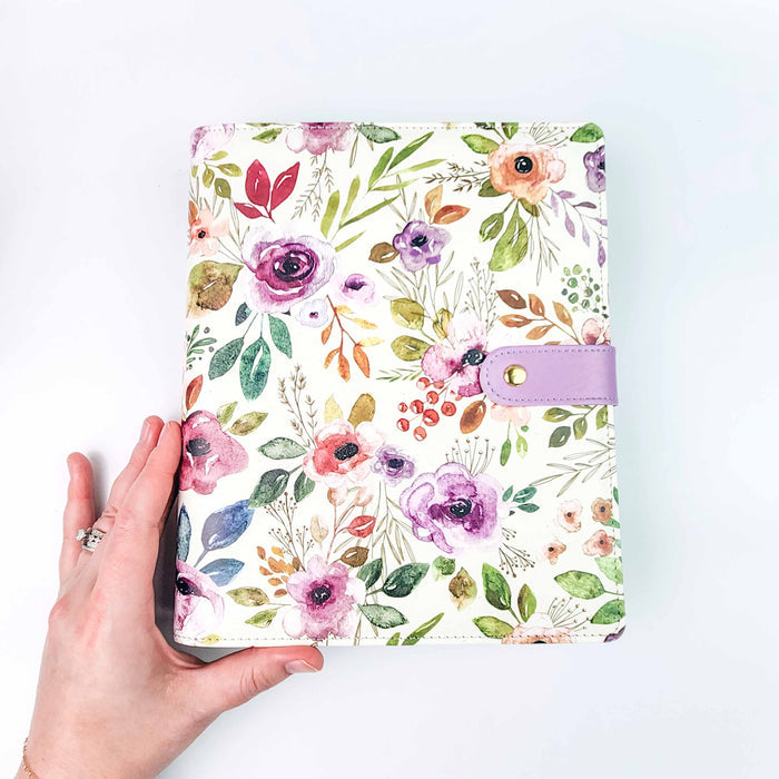Hand holding the Spring Floral Project Journal Planner showing the watercolor floral cover and lavender snap closure tab for size reference