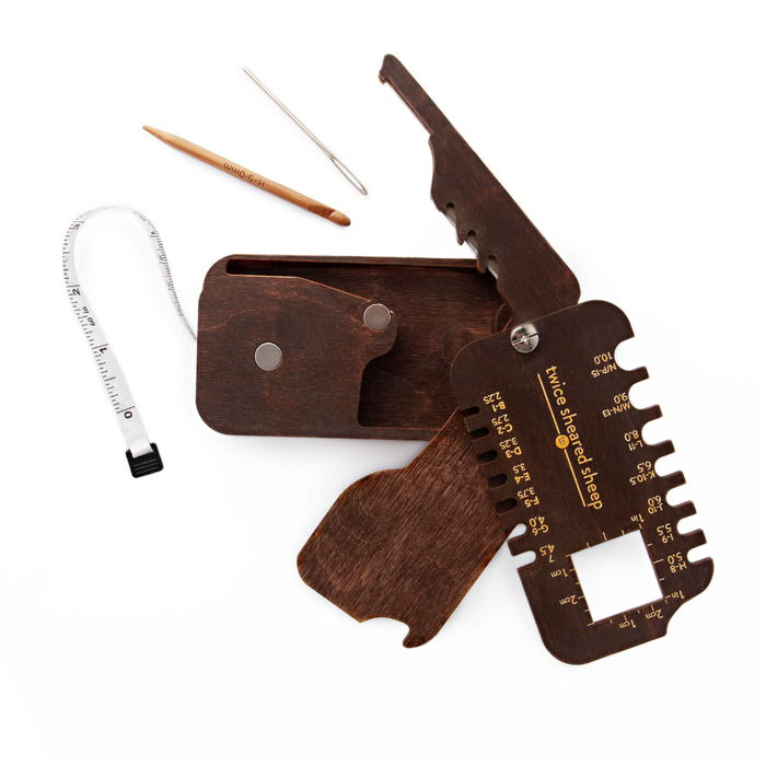 Stitch Scout Multi-Tool fully unfolded showing open storage box, extended measuring tape, cable needle, and darning needle