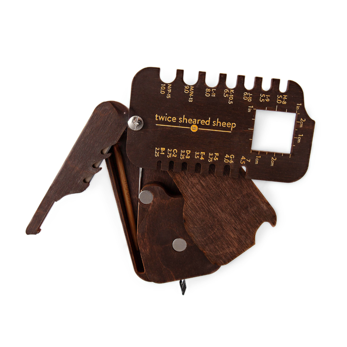 Stitch Scout Multi-Tool partially folded showing WPI tool, yarn cutter, and storage compartment with cable needle and darning needle inside