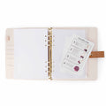Open pink leather project journal binder with gold rings, graph paper, and zippered pouch with pom-pom instructions