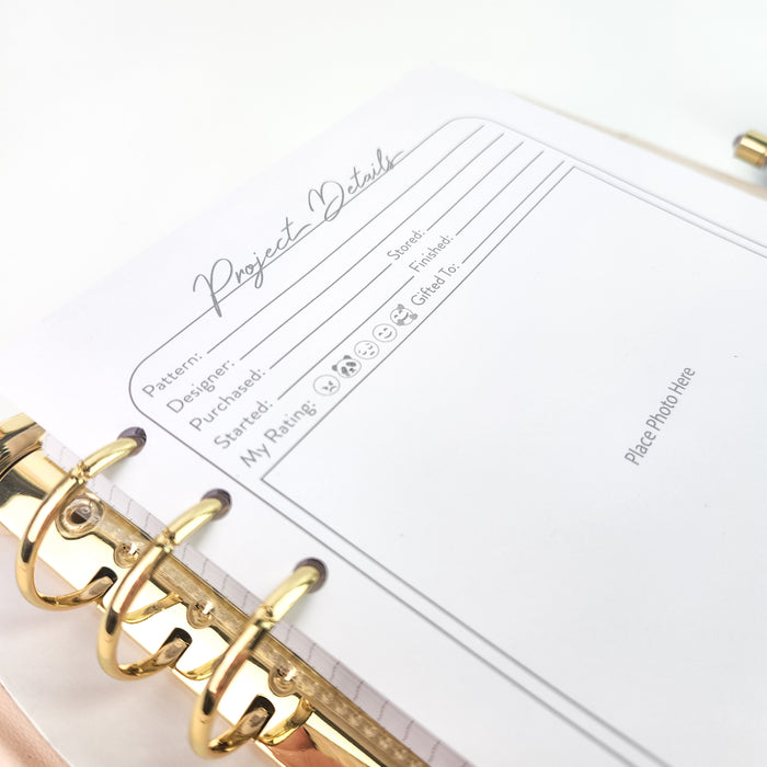Project Details divider page in pink binder with gold rings showing pattern, designer, and rating fields