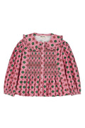 A pink long-sleeve children's blouse with a green and red floral pattern, featuring a ruffled collar and smocked bodice details, shown flat on a white background.