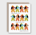 A birthday greeting card with a kraft envelope behind it. The card features a grid of cartoon dogs wearing colorful striped outfits and the text 'happy birthday to you!' printed below each dog.