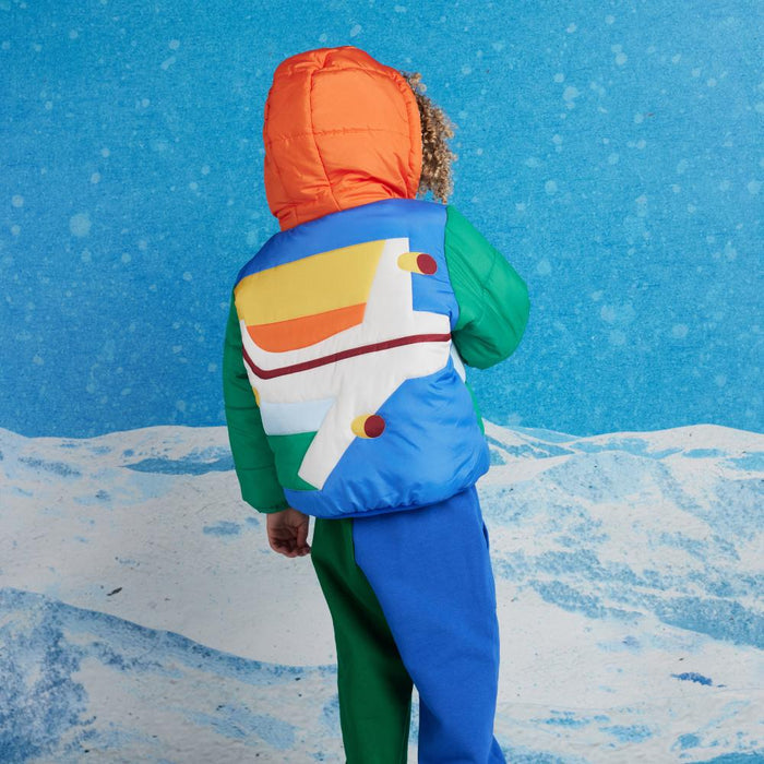 Child wearing a colorful jacket with a blue background