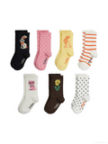 Six pairs of children's socks arranged in two rows on a plain white background. The socks come in black, pink, yellow, white, brown, and orange, each with a different animal or flower illustration and some form of pattern (stripes, polka dots, or white dots).