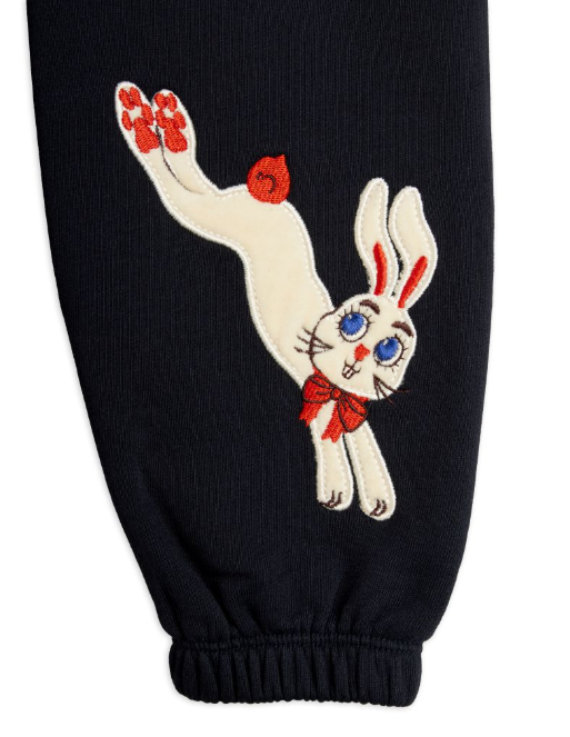 Close-up of pants leg, featuring an embroidered white rabbit with blue eyes, red bow, and red paw pads.