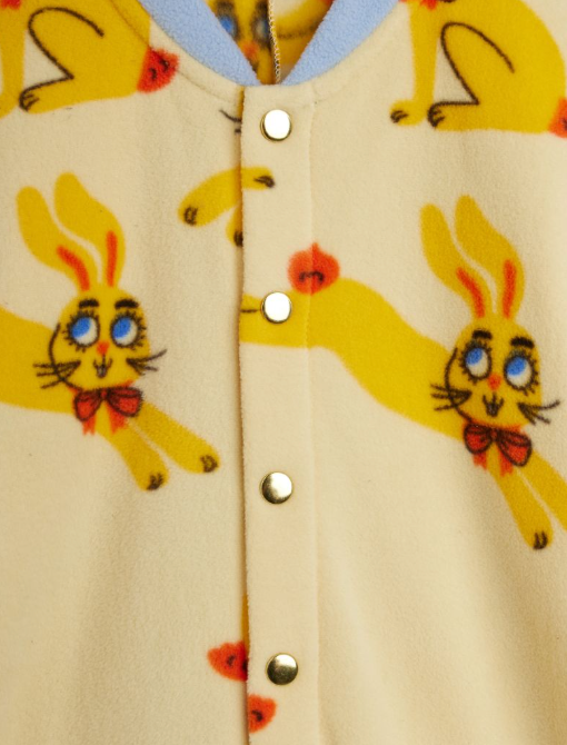 Close-up of a fleece romper with a yellow cartoon bunny print, featuring a snap-button front closure and a light blue inner collar.