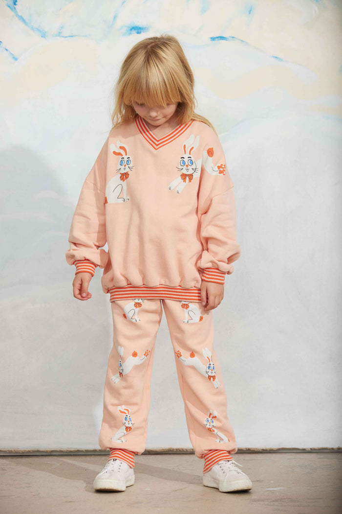 Child wearing a matching pink outfit with animal prints against a light background
