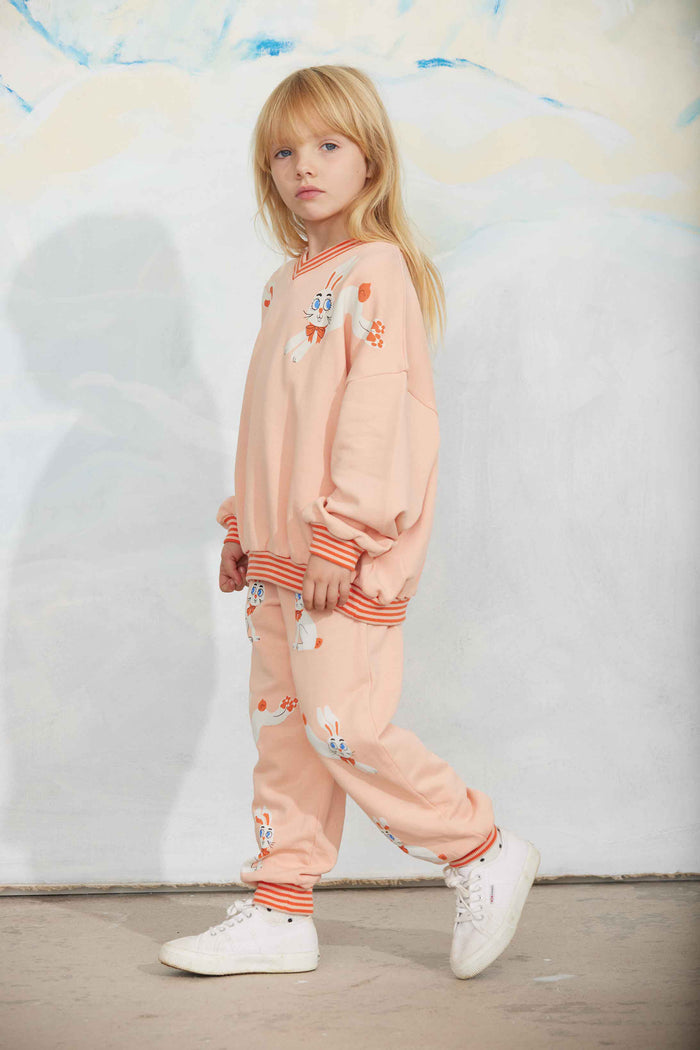 Child wearing a peach-colored outfit with cartoon character designs against a light gray background