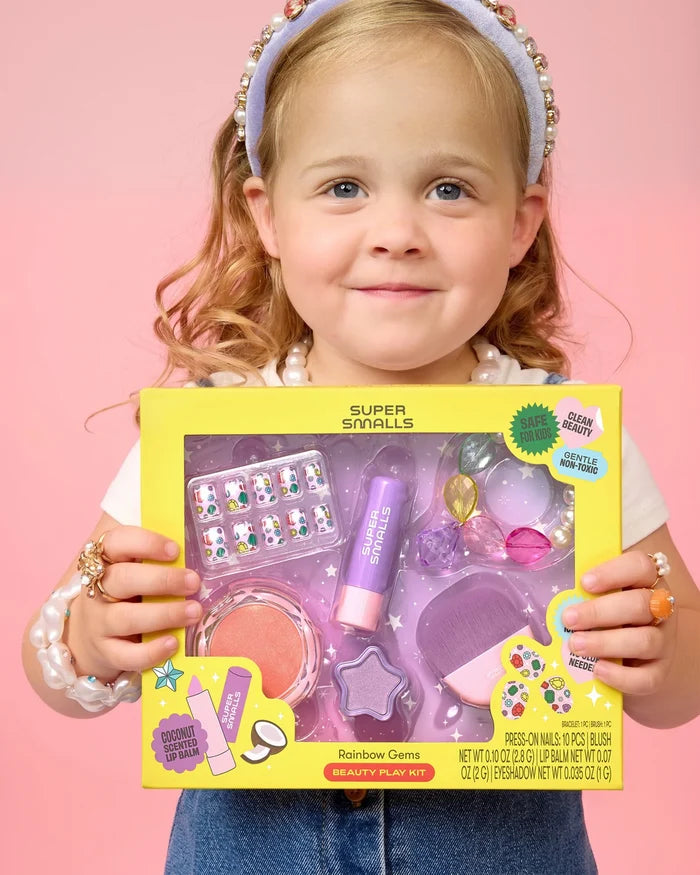Child holding a Super Snails beauty play kit against a pink background