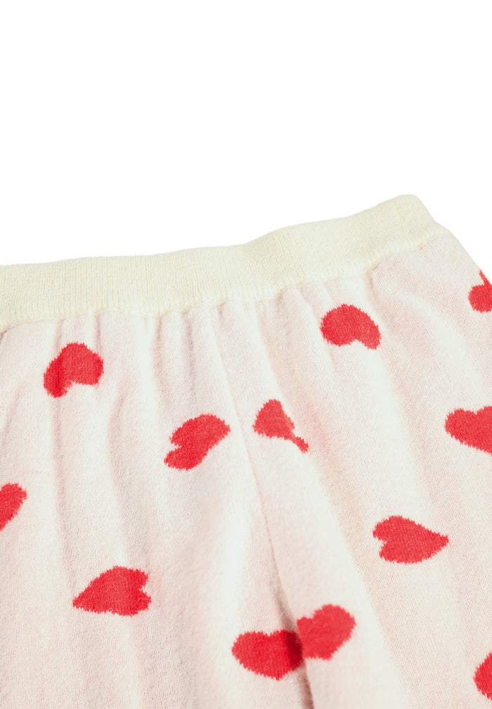 Close-up of a cream-colored fabric with red heart patterns on a white background