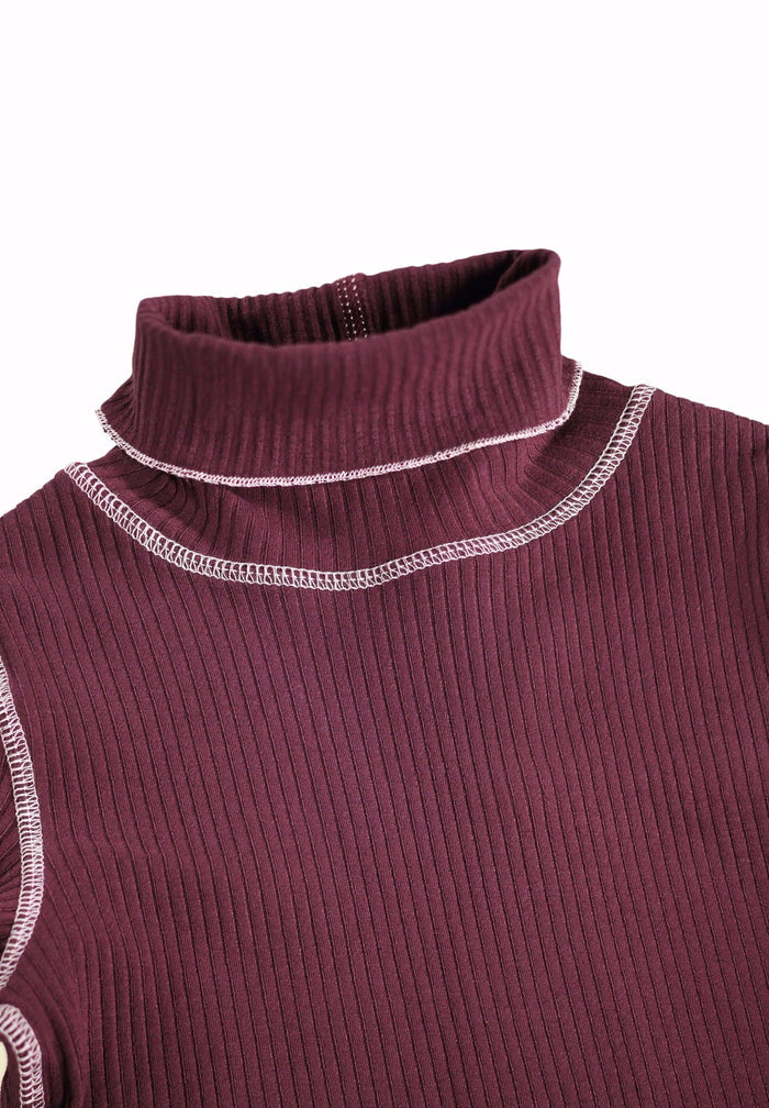 Close-up of a ribbed turtleneck sweater with white trim on a white background