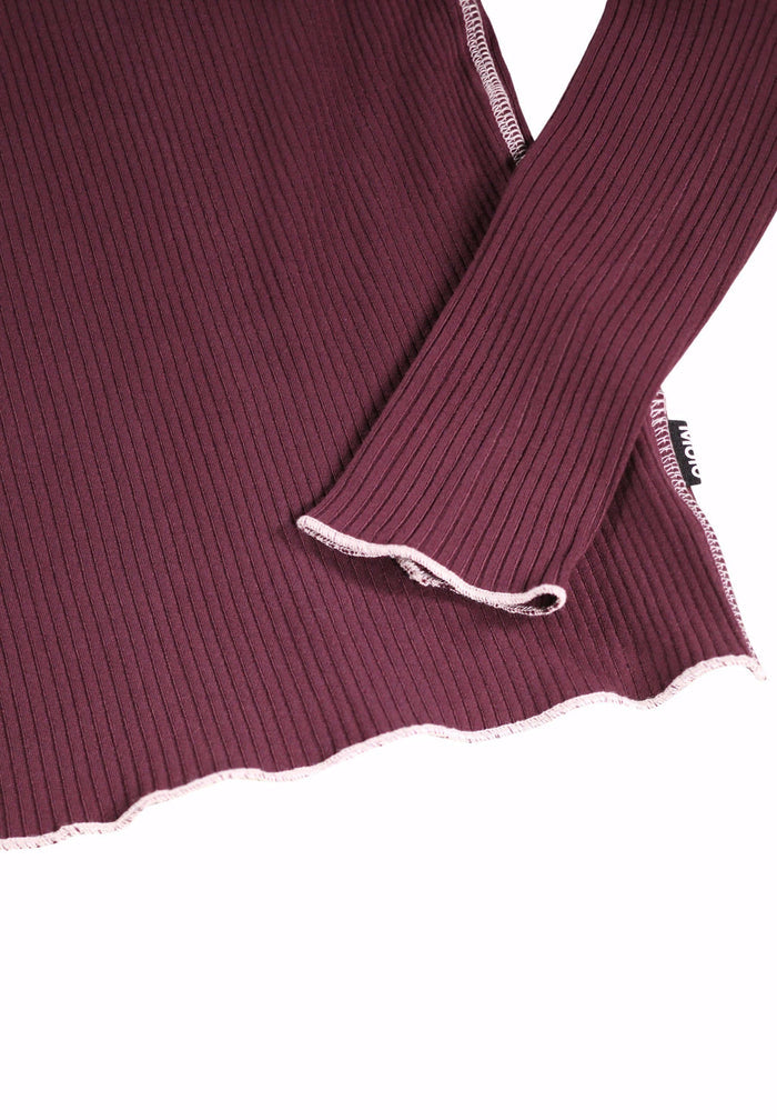 Close-up of a ribbed knit garment with lace trim on a white background