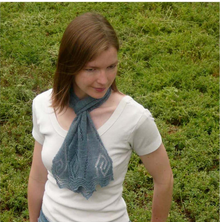 Woman wearing gray-blue Rill lace scarf tied at front showing pointed leaf lace border ends