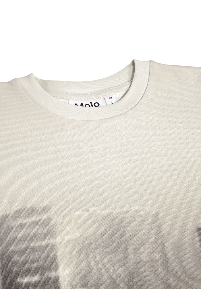 Close-up of a beige t-shirt with a blurred design on a white background