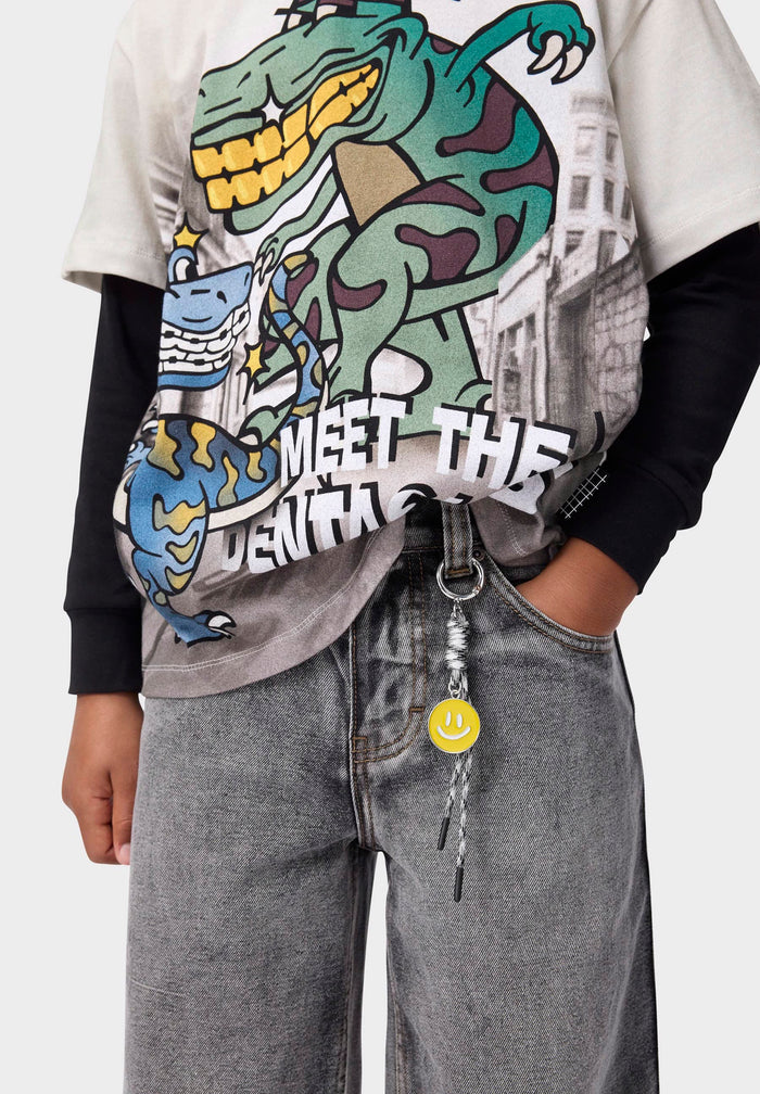 Person wearing a graphic t-shirt with a dinosaur design and gray pants on a white background