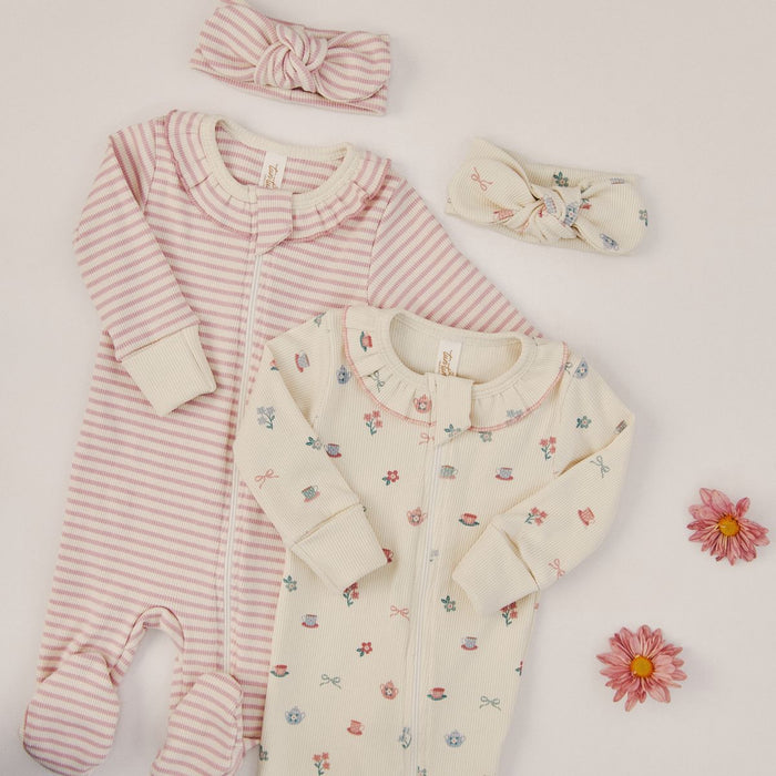 Baby romper, floral top, and headbands on a light background with flowers.