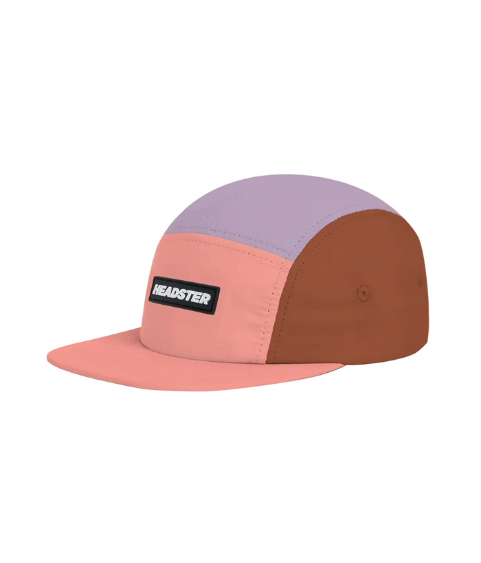A color-blocked 5-panel cap by Headster, featuring a light purple crown, a dusty pink front panel and brim, and a brown side panel, with a black rectangular logo patch on the front.