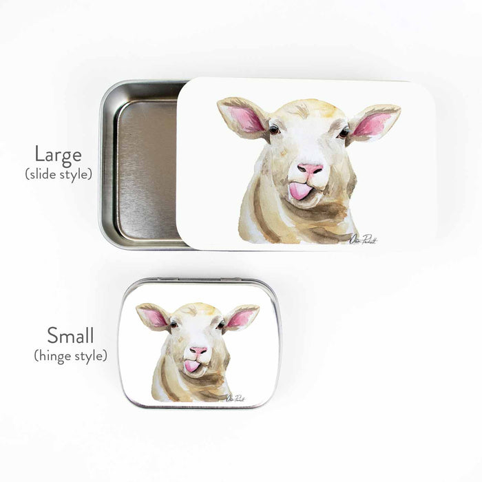 Sassy Sheep storage tin side-by-side size comparison showing the large slide style and small hinge style, both featuring the watercolor tongue-out sheep portrait by Dawn Prickett