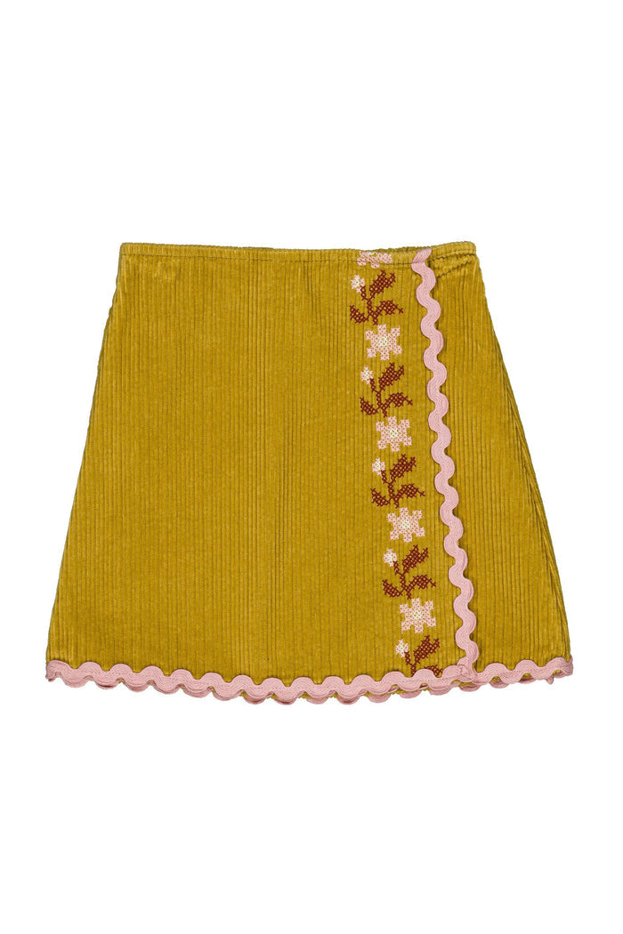 A mustard yellow corduroy mini skirt with a pink scalloped border and a vertical embroidered floral pattern down the side.